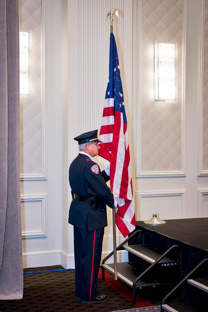 An officer standing next to the American Flag.